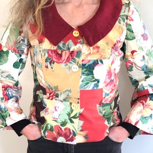 May include: A patchwork jacket with a floral print and a burgundy corduroy collar. The jacket has long sleeves and a button closure.