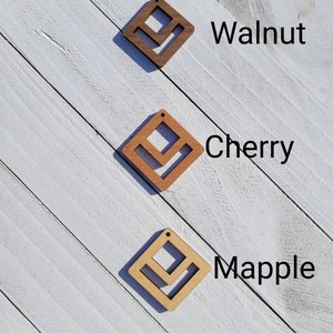 May include: Three wooden diamond-shaped earrings in walnut, cherry, and maple wood.