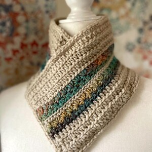 May include: A crocheted neck warmer in a beige color with a multi-colored stripe detail. The stripe features shades of teal, brown, yellow, and orange.