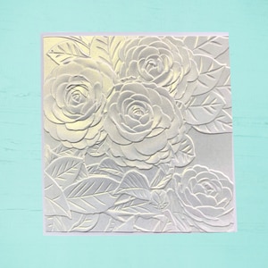 Tarjeta de felicitación bellamente grabada con un impresionante ramo de rosas blancas perladas.