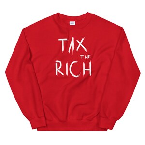 May include: A red sweatshirt with the white text "TAX THE RICH" in a bold, brushstroke style. The crew neck sweatshirt is a solid red color, with the text centered on the chest.