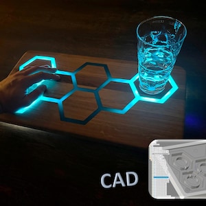 May include: A wooden serving tray with a honeycomb design and blue LED lights. The tray is lit up and a glass of water is sitting on top of it. The text "CAD" is visible in the lower right corner of the image.