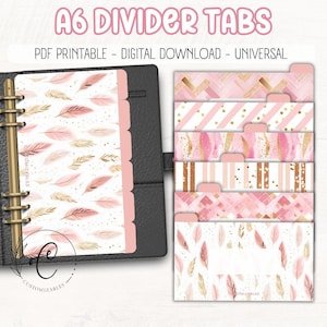 May include: A6 divider tabs with a pink and gold feather design, and the text "A6 DIVIDER TABS PDF PRINTABLE - DIGITAL DOWNLOAD - UNIVERSAL". The tabs are shown in a black binder.