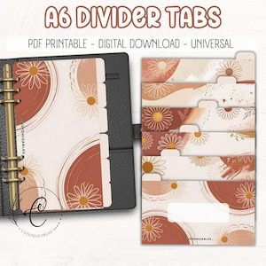 May include: A6 divider tabs with a floral design in shades of brown, beige, and white. The tabs are labeled "A6 DIVIDER TABS" and include the text "PDF PRINTABLE - DIGITAL DOWNLOAD - UNIVERSAL". The tabs are shown in a black binder.