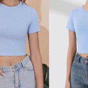 Peut inclure: Haut court bleu clair &agrave; col rond et manches courtes. Le haut est associ&eacute; &agrave; un jean en denim bleu. L'image pr&eacute;sente une tenue d&eacute;contract&eacute;e, id&eacute;ale pour le temps chaud ou pour superposer.