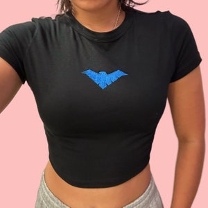 May include: Black cropped t-shirt with a blue embroidered bird design.