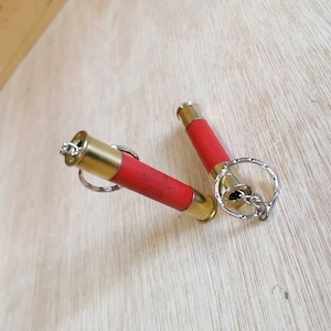 May include: Two red and gold shotgun shell keyrings with a silver chain and ring.