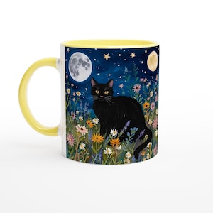 May include: A yellow and white ceramic mug featuring a black cat sitting in a field of flowers beneath a crescent moon and stars. The mug has a yellow rim and handle.