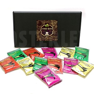 May include: A black box with the text "CHAI BOX" on the lid. The box contains 10 individual packets of Royal Chai tea, each with a different flavour and colour.