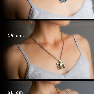 May include: Three silver chains with different lengths, 40 cm, 45 cm, and 50 cm, are shown with a pendant on each. The pendants are square and feature different mosaic designs. The top pendant is blue with red accents, the middle pendant is green and gold with a white centre, and the bottom pendant is green with black accents.