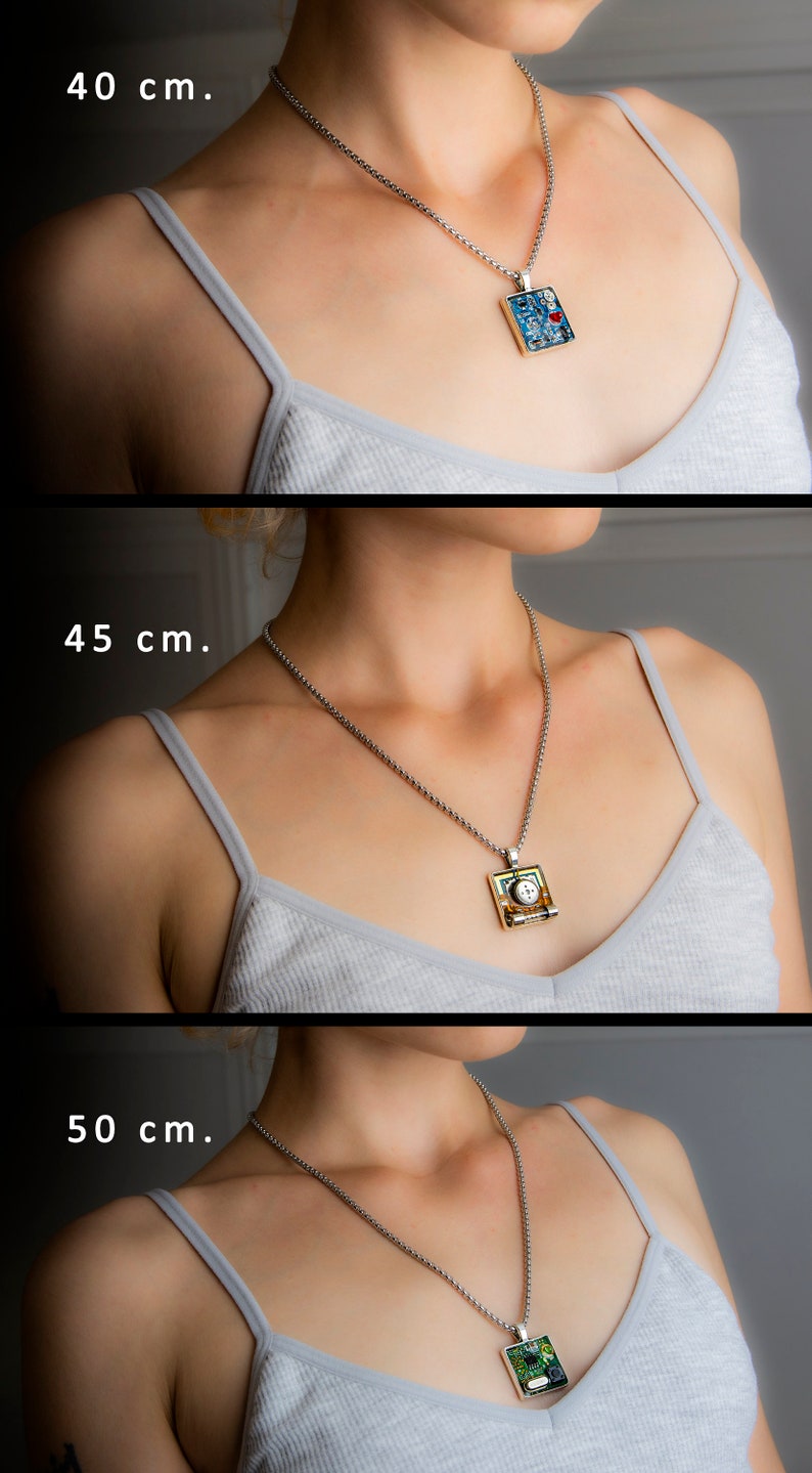 May include: Three silver chains with different lengths, 40 cm, 45 cm, and 50 cm, are shown with a pendant on each. The pendants are square and feature different mosaic designs. The top pendant is blue with red accents, the middle pendant is green and gold with a white centre, and the bottom pendant is green with black accents.