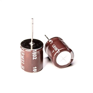 Könnte beinhalten: Zwei braune zylindrische Kondensatoren mit silbernen Oberteilen und weißem Text. Der Text auf dem linken Kondensator lautet "1602 - 16(  " und "WERMEI H". Der Text auf dem rechten Kondensator lautet "LS105 C" und "85°C".