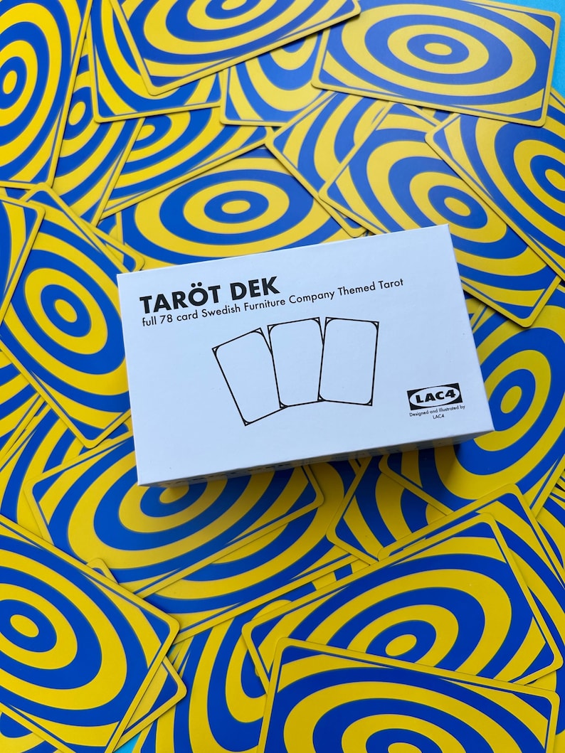 May include: A deck of Tarot cards with a blue and yellow spiral design. The box reads "TAROT DEK full 78 card Swedish Furniture Company Themed Tarot". The cards are scattered around the box.