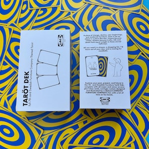 May include: A tarot deck with a white box featuring the text "TAR&Ouml;T DEK" and "full 78 card Swedish Furniture Company Themed Tarot." The deck includes cards with blue and yellow concentric circle designs. The box has text describing the deck.