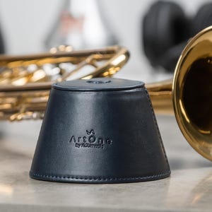 May include: A dark blue leather trumpet mute with the text "Artone by Raummusik" on the side.