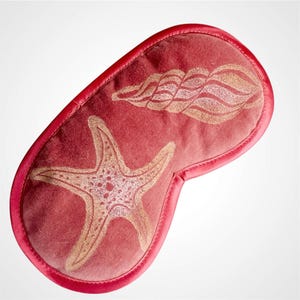 Könnte beinhalten: Eine korallenfarbene Schlafmaske mit einem Seestern- und Muscheldesign. Die Maske hat einen Satinrand und ist so konzipiert, dass sie das Licht blockiert. Der Seestern und die Muschel sind hellbraun.