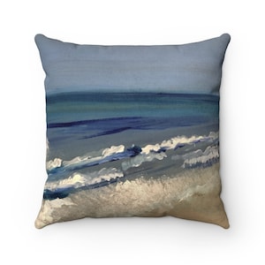 May include: A throw pillow with a painting of a blue ocean with white waves crashing on the shore. The sky is a light blue.