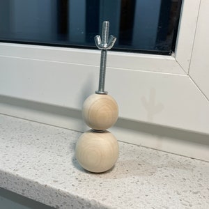 May include: A wooden snowman ornament with two round wooden balls stacked on top of each other. The top ball has a metal screw with a star-shaped top.