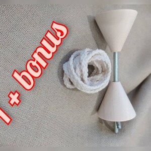 May include: A set of two wooden cones with a metal rod connecting them. The cones are a light pink colour and have a smooth finish. A white cotton rope is included. The text "1+ bonus" is written in red on a white background.