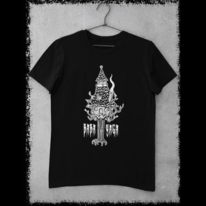May include: Black t-shirt with a white graphic of a house on stilts with the text "Baba Yaga" underneath. The t-shirt is hanging on a hanger.