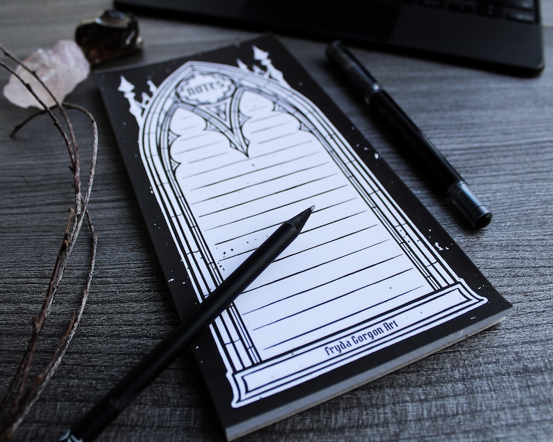 May include: Black and white notepad with a gothic arch design. The notepad has lined pages and the text "Fryda Gorgon Art" at the bottom.
