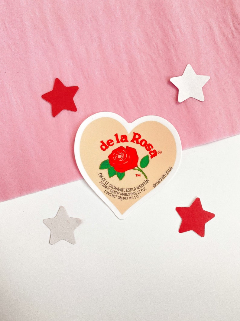 May include: A heart-shaped sticker featuring the words "de la Rosa" and a red rose design. The sticker also includes text about peanut candy and the phrase "@THECHISTOSASCLUB." Four star-shaped cutouts in red and white surround the sticker.
