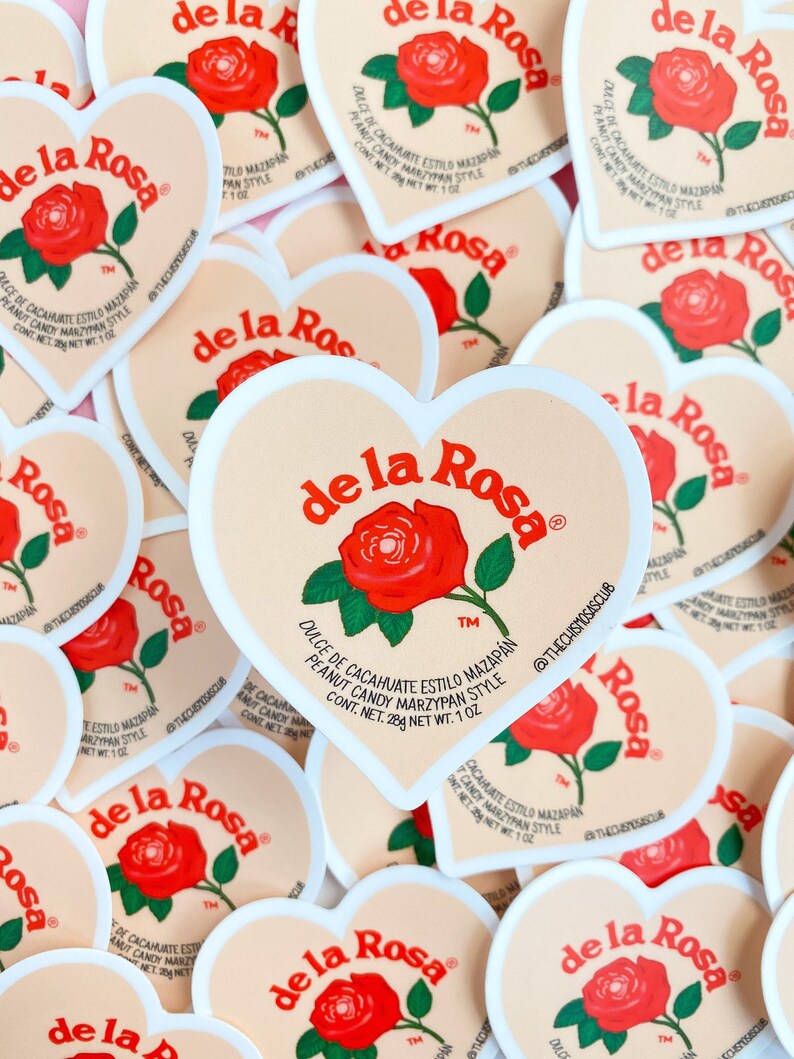 May include: Heart-shaped stickers with a light peach background and a white border. Each sticker features the "de la Rosa" logo, a red rose illustration, and text in Spanish. The text includes "Dulce de Cacahuate Estilo Mazapan" and "Peanut Candy Marzipan Style."