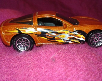 A Chevrolet Corvette C5 toy car by Mattel, in rust colour, with flames painted on both sides