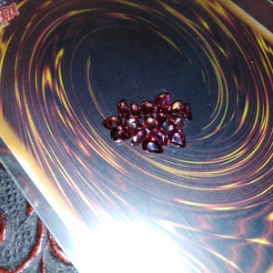 Puede incluir: Primer plano de un montón de pequeñas piedras preciosas rosadas en forma de corazón sobre un fondo negro y dorado.