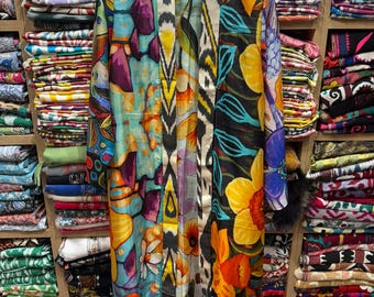 May include: A long, open-front kimono-style robe with a vibrant floral and geometric pattern. The robe features a mix of colors including blue, orange, yellow, and purple. The sleeves are long, and the robe is hanging on a hanger.