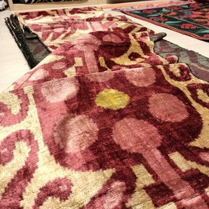 May include: A folded pink and gold patterned fabric with a geometric design. The fabric has a soft, velvety texture.