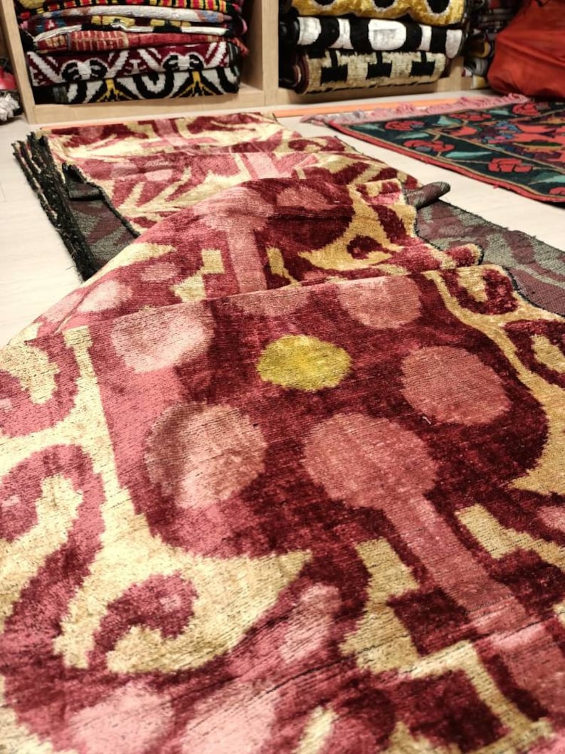 May include: A folded pink and gold patterned fabric with a geometric design. The fabric has a soft, velvety texture.