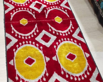 May include: Red and white ikat fabric with a repeating pattern of yellow circles and diamond shapes. The fabric is woven with a raised texture.