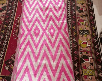 May include: A stack of pink and white fabric with a chevron pattern. The fabric is folded and has a frayed edge.