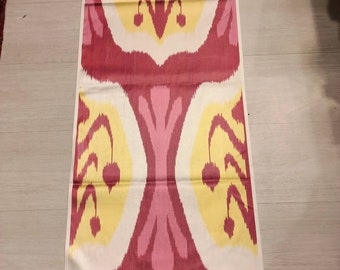 May include: A red, white, and yellow fabric with a repeating pattern of stylized flowers and leaves. The fabric has a soft, silky texture.