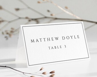 May include: White place card with a black border. The text "MATTHEW DOYLE" is printed in black at the top and "TABLE 3" is printed in black below.