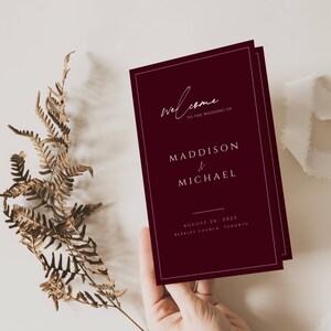 Może przedstawiać: Program ślubny w kolorze bordowym z białym tekstem. Program zawiera napis "Witamy na ślubie Maddison & Michael" oraz datę i miejsce ślubu.