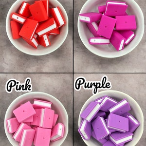 Könnte beinhalten: Vier weiße Schalen gefüllt mit bunten bücherförmigen Perlen. Die Schalen enthalten rote, fuchsiafarbene, rosa und violette Perlen mit weißen Akzenten. Die Wörter "Red", "Fushia", "Pink" und "Purple" stehen über jeder Schale.