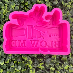 Op de afbeelding: Roze siliconen mal voor het maken van een cake of koekje met de woorden "Blow Me" en een silhouet van een jager met een geweer en vliegende eenden.
