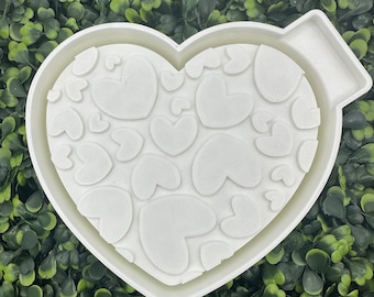 May include: White heart-shaped silicone mold with a raised design of multiple hearts. The mold has a small handle on the side.