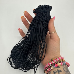Pode incluir: Um grande pacote de elásticos de cabelo pretos. Os elásticos estão agrupados e prontos para serem usados.