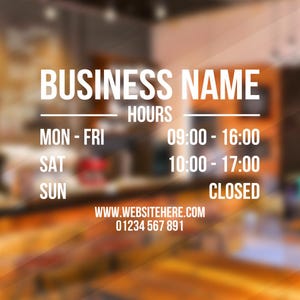 May include: A white sign with black text on a blurred background. The sign displays the business name, hours of operation, and contact information. The business is open Monday to Friday from 09:00 to 16:00, Saturday from 10:00 to 17:00, and closed on Sunday. The website is www.websitehere.com and the phone number is 01234 567 891.