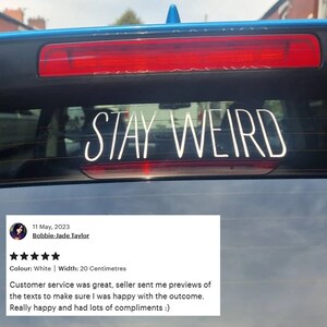 May include: A white vinyl car sticker with the text "STAY WEIRD" on a blue car. The sticker is 20 inches wide.
