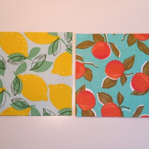May include: Two paper napkins with a summer fruit theme. One napkin has a yellow lemon pattern on a light blue background. The other napkin has a red orange pattern on a turquoise background.