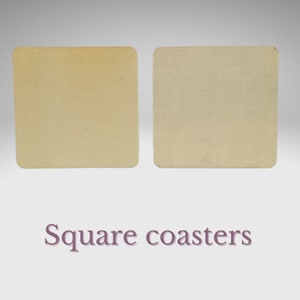 May include: Two square beige coasters. The coasters are made of a textured material and have a slightly rough surface.