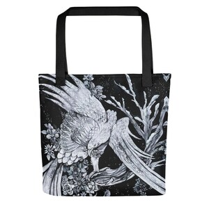 May include: A black tote bag with a white and gray design of a bird with intricate details. The bird is perched on a branch with flowers and leaves. The background is black with a starry pattern.