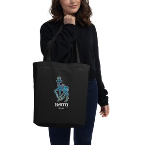May include: Black tote bag with a blue and yellow creature graphic and the text "NAITO Berlin".