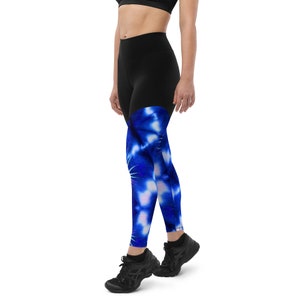 Könnte beinhalten: Schwarze Leggings mit einem blauen und weißen Batik-Muster an den Unterschenkeln. Die Leggings sind figurbetont und haben einen hohen Bund.