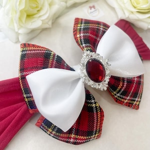 Puede incluir: Un lazo a cuadros rojos con detalles de sat&eacute;n blanco y un centro de joya roja brillante. El lazo est&aacute; sujeto a una diadema roja a juego. Accesorio decorativo para el cabello.