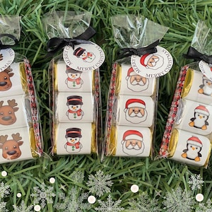 May include: Four cellophane bags filled with individually wrapped chocolate candies. Each bag is tied with a black ribbon and a circular tag that says "Merry Christmas." The candies feature festive images of reindeer, snowmen, Santa Claus, and penguins.